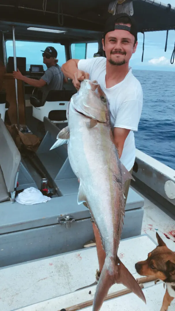 A man holding a large fish on top of a boat.