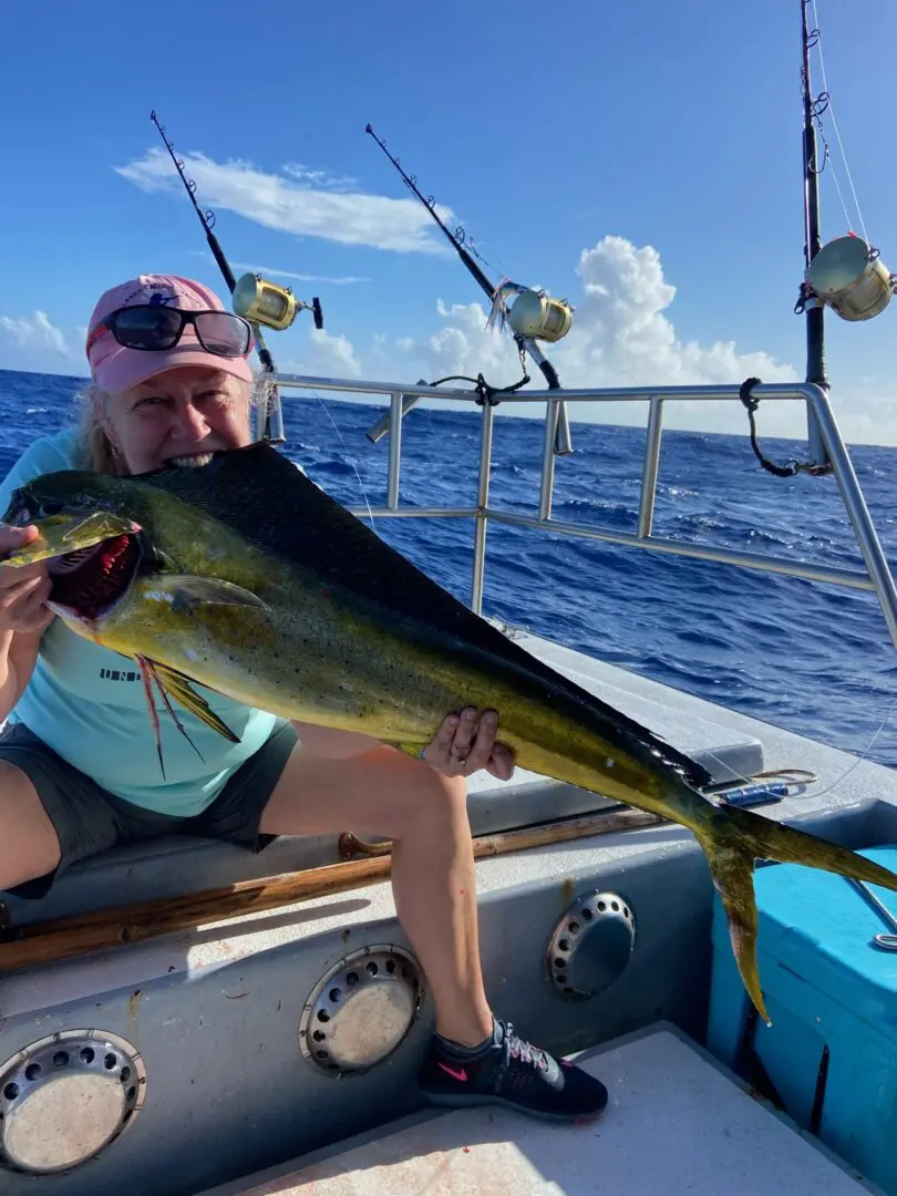 A man holding up a fish while sitting on the boat.