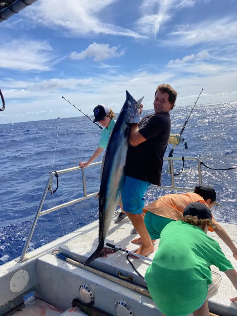 A man holding a fish while standing on the side of a boat.