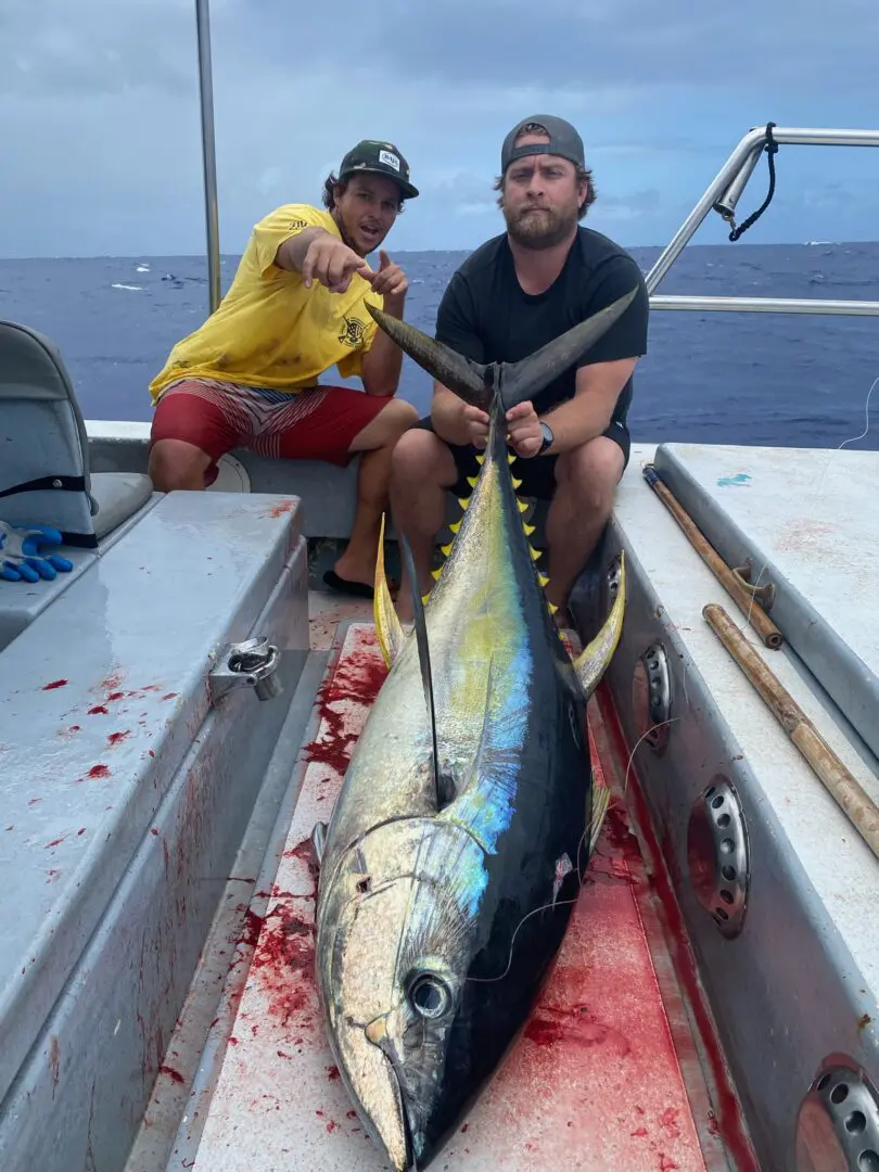 Two men sitting on a boat with a large fish.