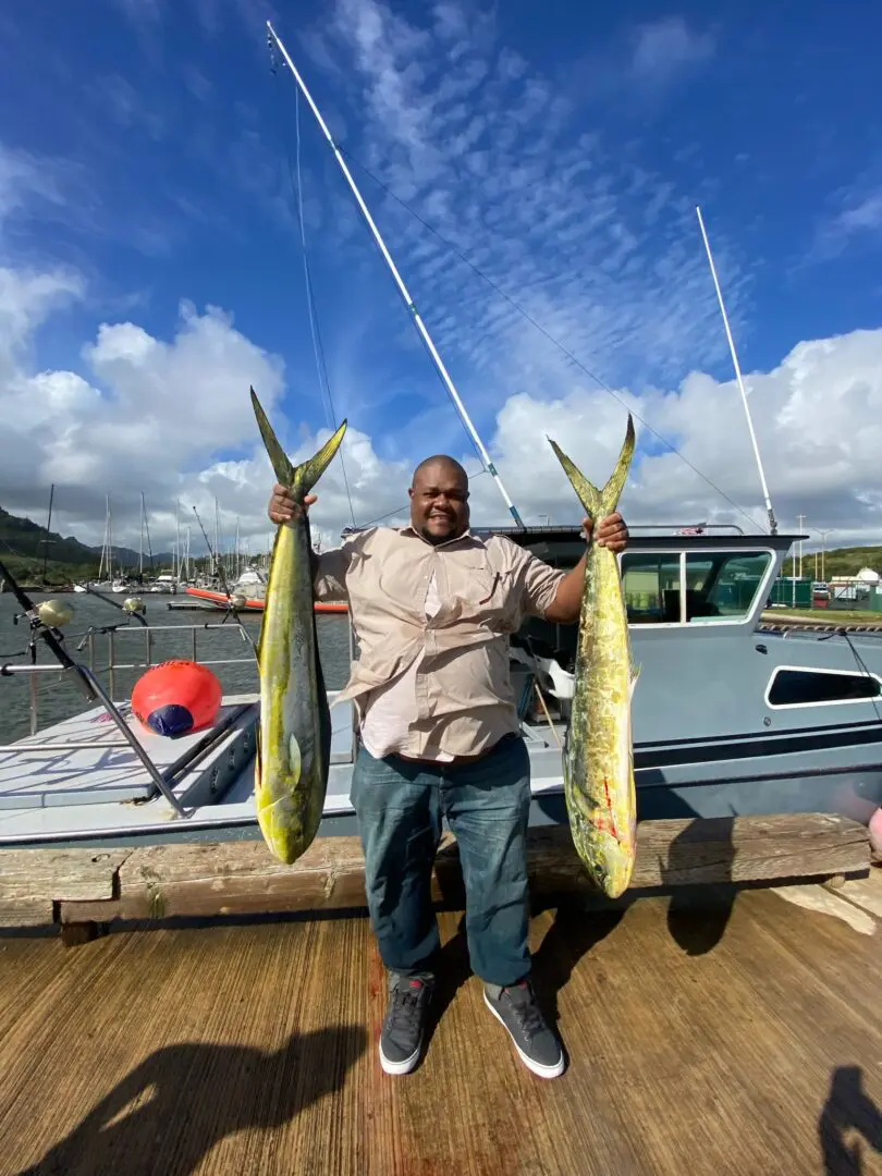 A man holding two fish on the dock