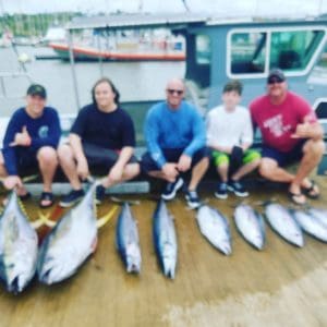 Group displaying caught fish on dock.