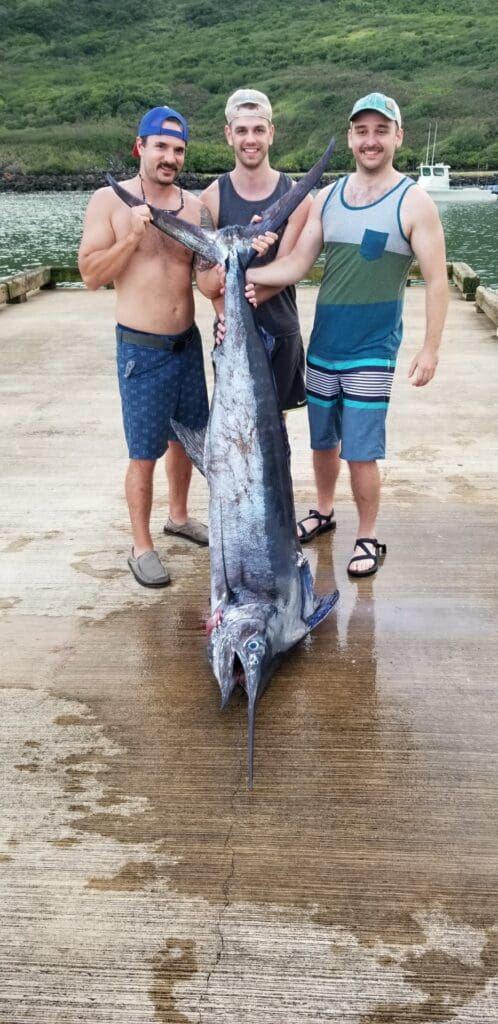 Three men holding a large caught fish.