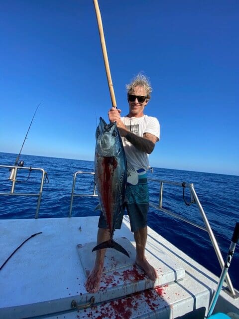 Person holding large fish on boat deck.