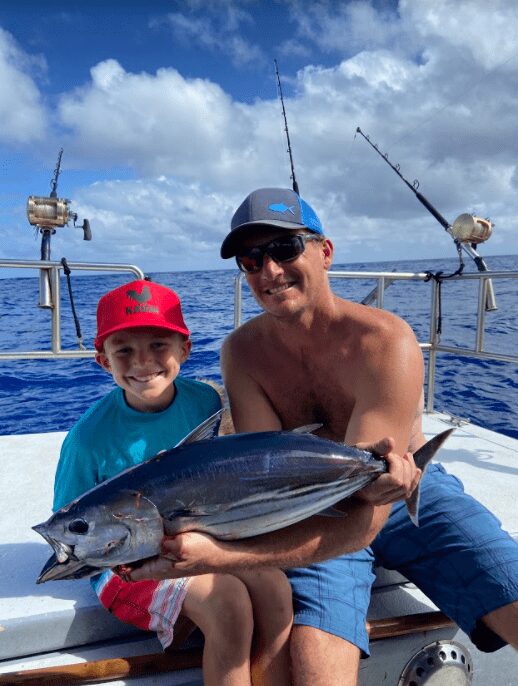 Man and child with large fish on boat.