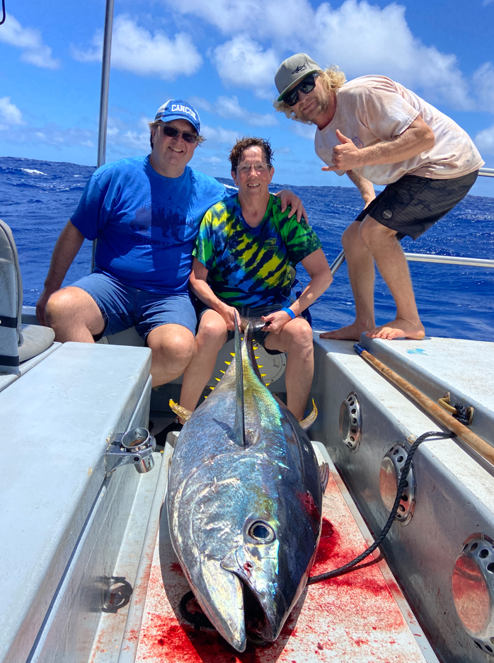 Three people with large tuna on boat.