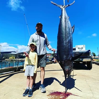 Man and child with large caught fish.