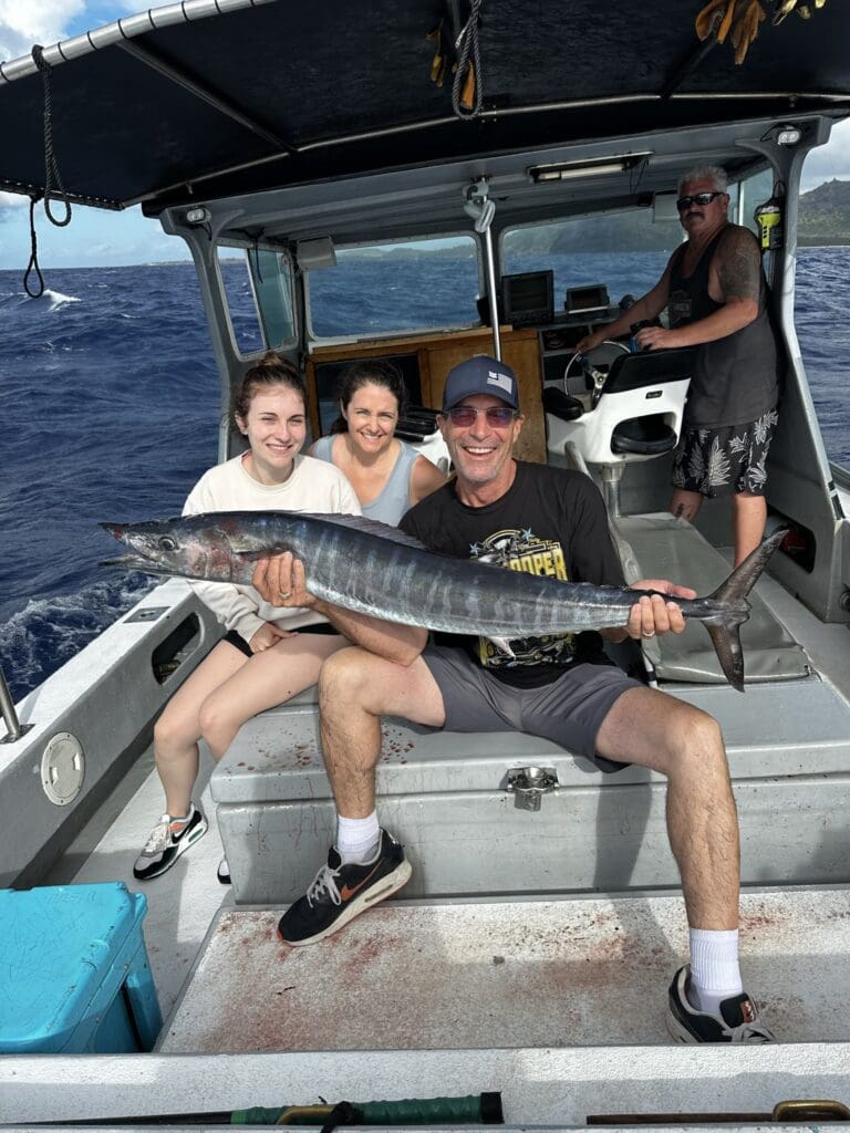 Group on boat holding large fish, smiling.
