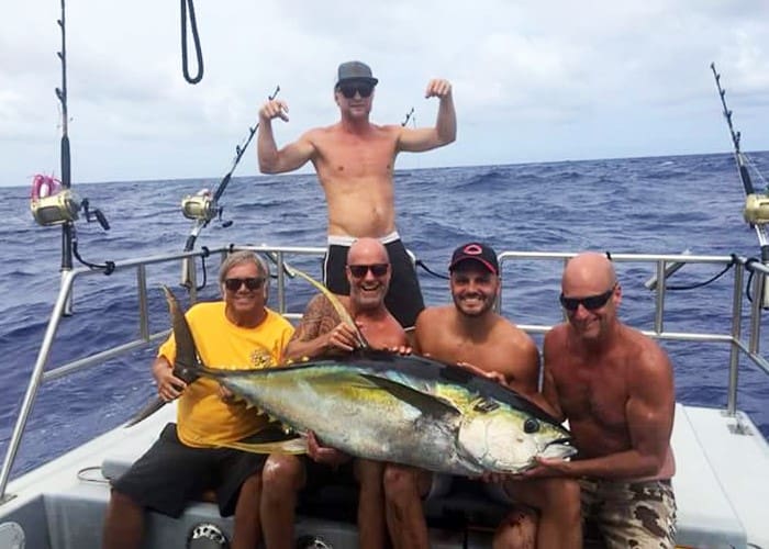 Group holding large fish on boat.