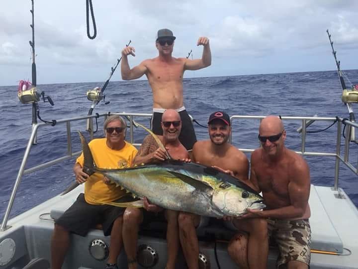 Group holding large fish on boat deck.