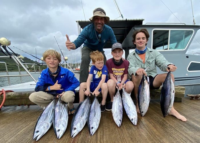 Group of people displaying freshly caught fish.
