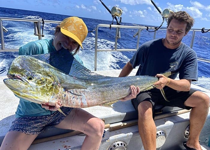 Two people holding a large fish on boat.