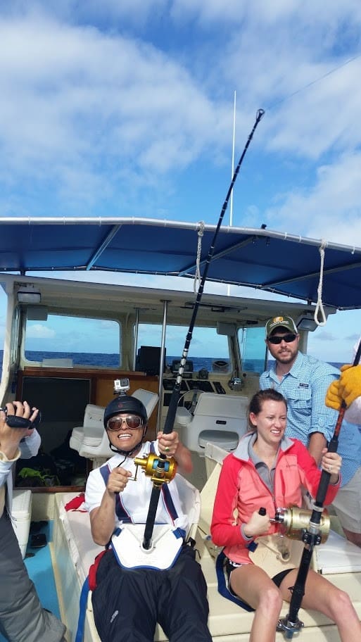 People fishing on a boat under blue sky.